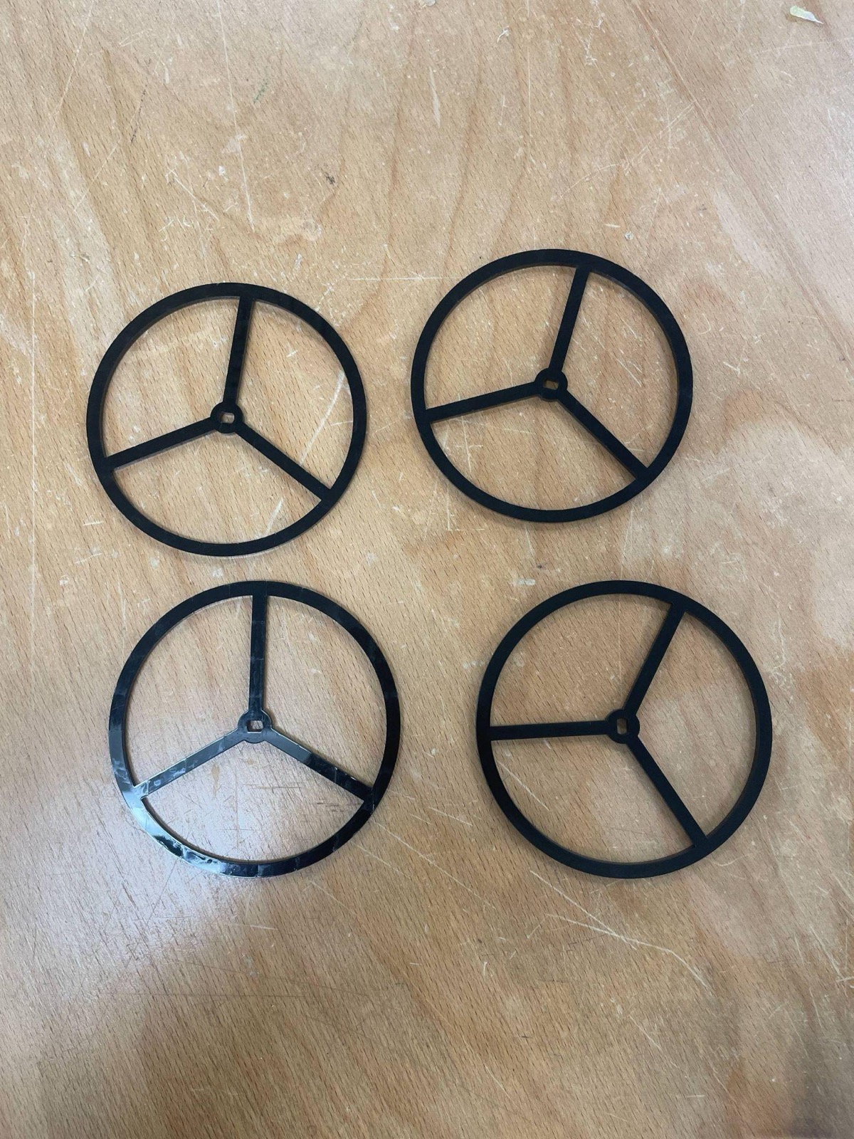 Four smooth black laser-cut wheels on a wooden table